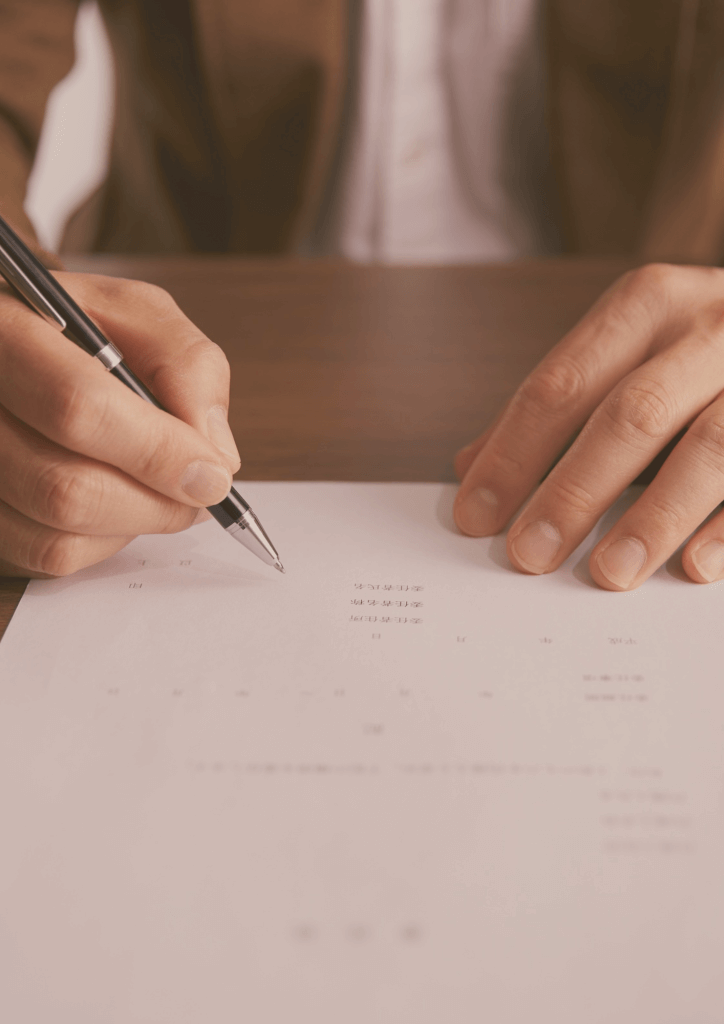 Zoom sur les mains d'un homme tenant un stylo et s'apprêtant à signer un contrat